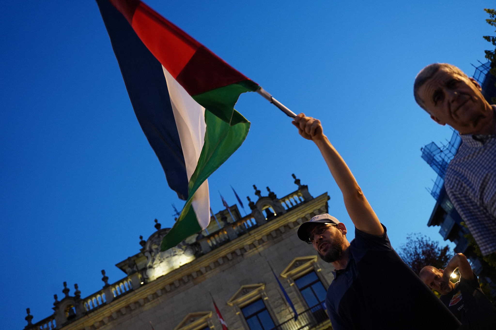 Pertsona bat bandera palestinar bat altxatzen Irungo udaletxearen aurrean